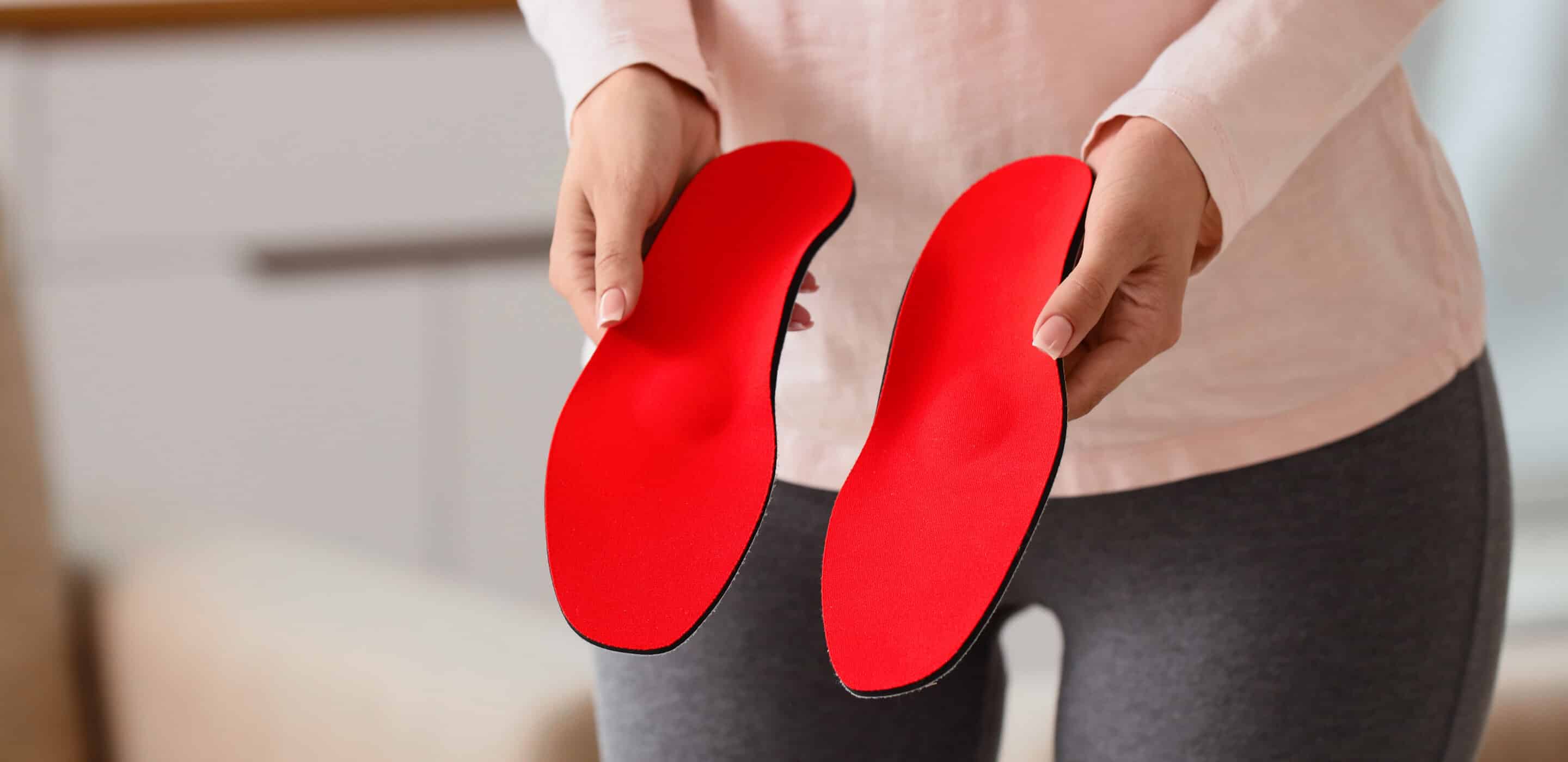 Orthopedic foot care and podiatry, woman holding custom shoe insoles for arch support and pain relief in a clinical or home setting Orthopedic foot care and podiatry, woman holding custom shoe insoles for arch support and pain relief in a clinical or home setting